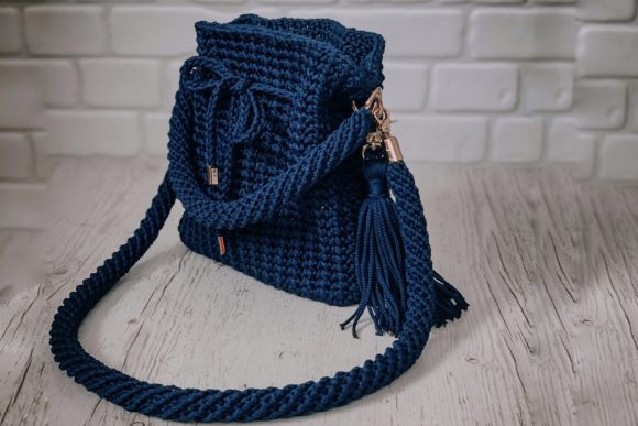 Handmade blue cord crochet bag with tassel on wooden table